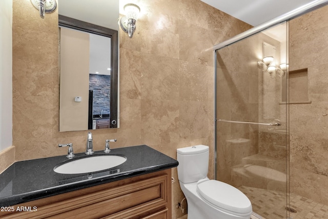 bathroom featuring vanity, a shower stall, toilet, and tile walls