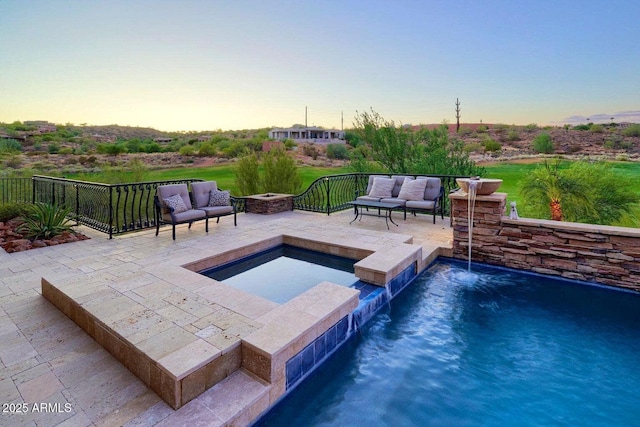 pool at dusk featuring an outdoor living space with a fire pit and a patio