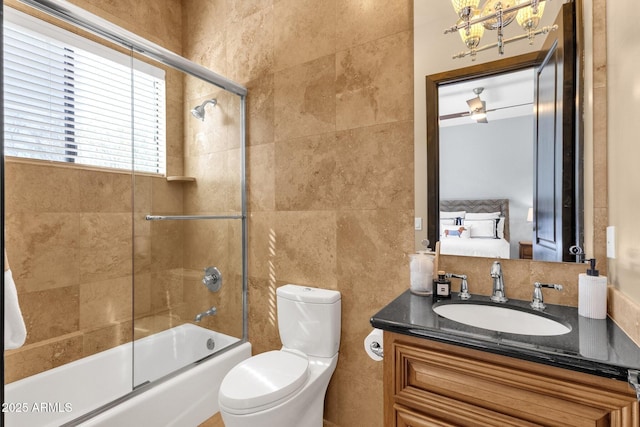 full bathroom with tile walls, toilet, ensuite bathroom, shower / bath combination with glass door, and vanity