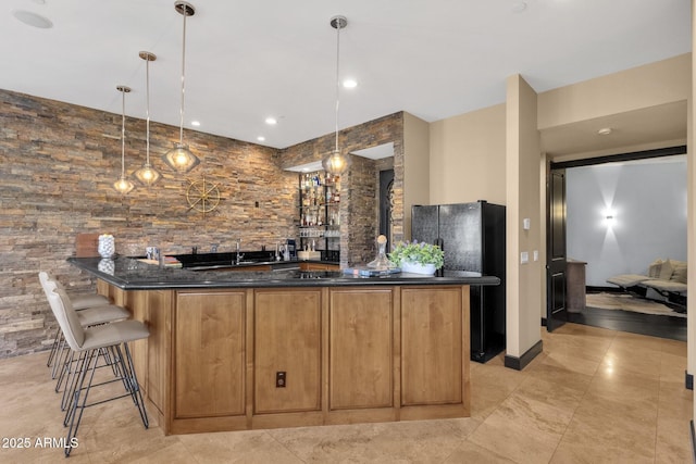 bar featuring indoor wet bar, freestanding refrigerator, and decorative light fixtures