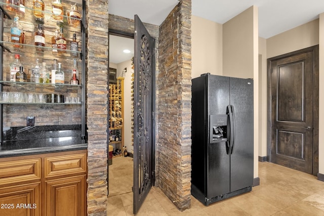 kitchen with brown cabinets, black fridge with ice dispenser, and light tile patterned flooring