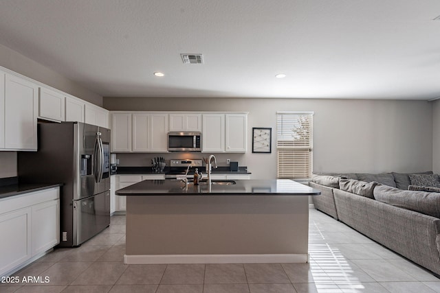 kitchen featuring stainless steel appliances, an island with sink, light tile patterned floors, white cabinets, and sink