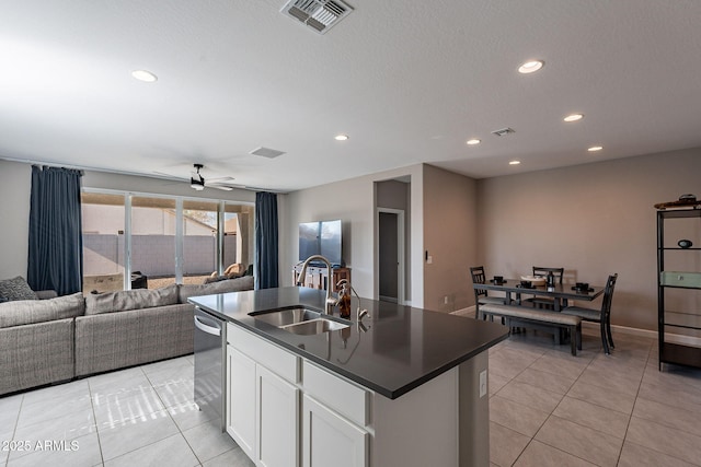 kitchen with white cabinets, a center island with sink, light tile patterned flooring, and sink