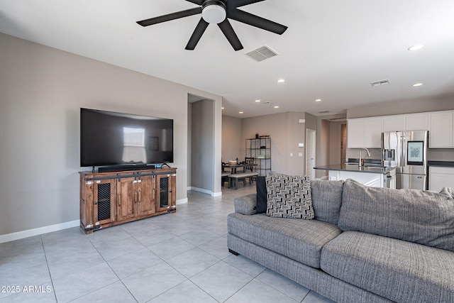 tiled living room featuring ceiling fan and sink