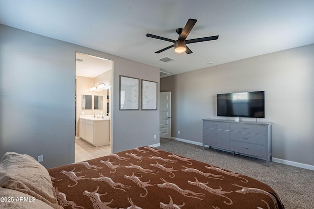 bedroom featuring ensuite bathroom, light colored carpet, and ceiling fan