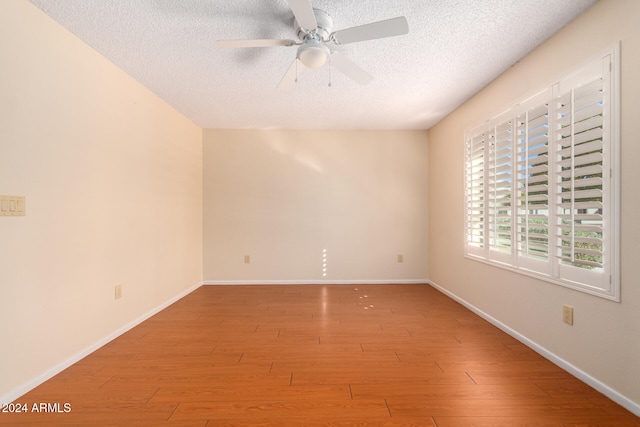 spare room with ceiling fan, light hardwood / wood-style floors, and a textured ceiling