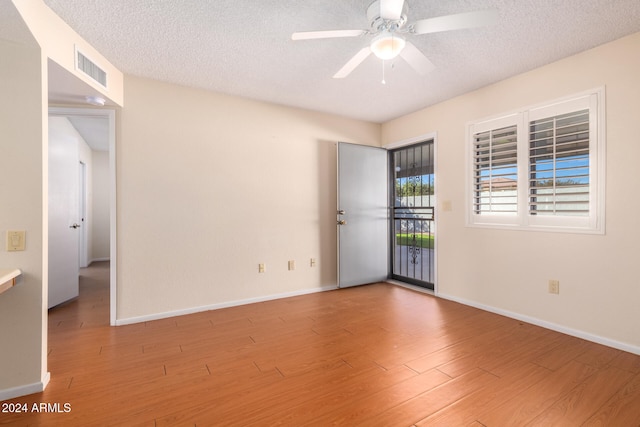 unfurnished room featuring a textured ceiling, light wood-type flooring, and ceiling fan