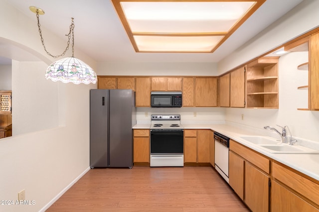 kitchen with sink, decorative light fixtures, white appliances, and light hardwood / wood-style flooring