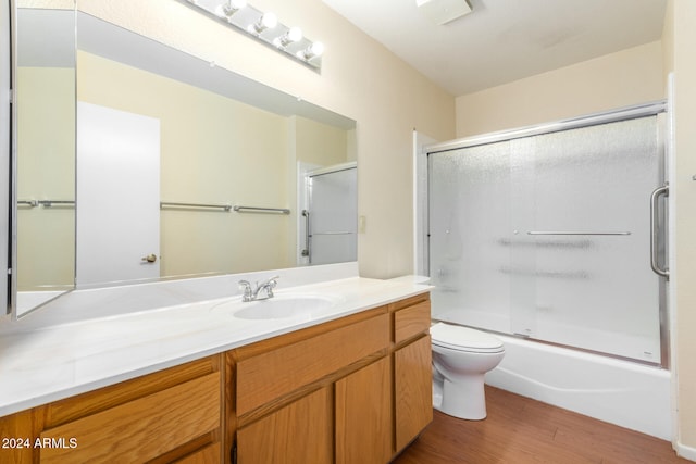 full bathroom featuring enclosed tub / shower combo, vanity, wood-type flooring, and toilet