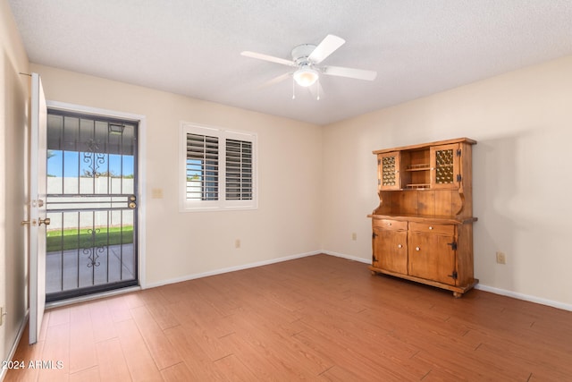 empty room with a textured ceiling, light hardwood / wood-style floors, and ceiling fan