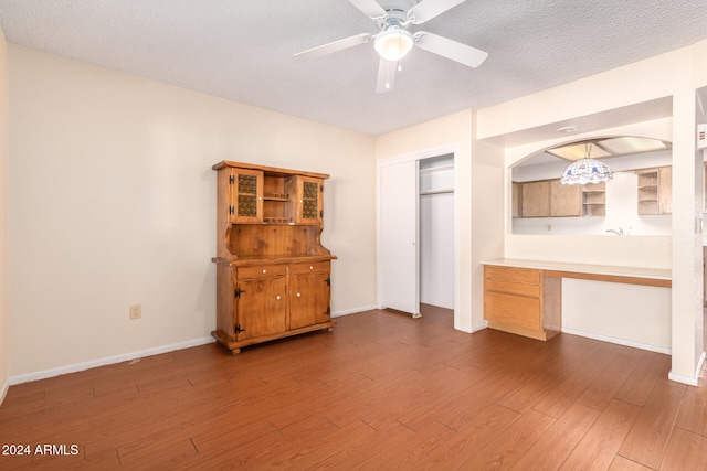 interior space with ceiling fan, hardwood / wood-style floors, built in desk, and a textured ceiling