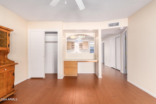 unfurnished bedroom with a closet, a textured ceiling, light hardwood / wood-style floors, and ceiling fan