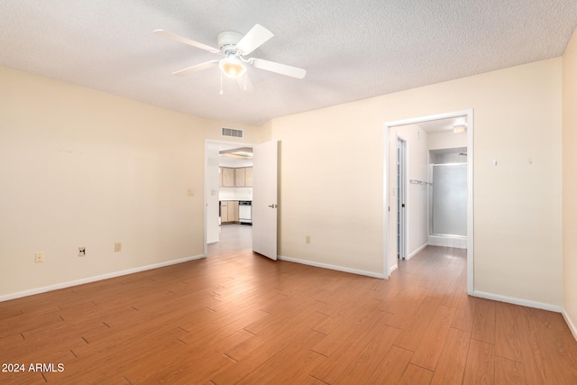 spare room featuring ceiling fan, light hardwood / wood-style flooring, and a textured ceiling