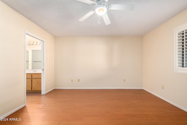 unfurnished room with ceiling fan, a textured ceiling, and light wood-type flooring