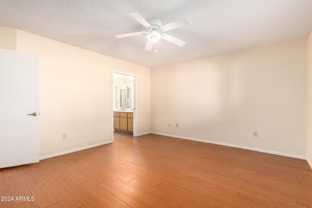 spare room featuring a textured ceiling, light wood-type flooring, and ceiling fan