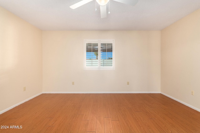 empty room with ceiling fan, wood-type flooring, and a textured ceiling