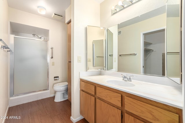 bathroom featuring vanity, toilet, wood-type flooring, and a shower with door