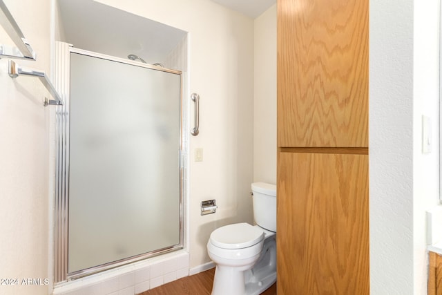 bathroom with hardwood / wood-style flooring, toilet, and walk in shower