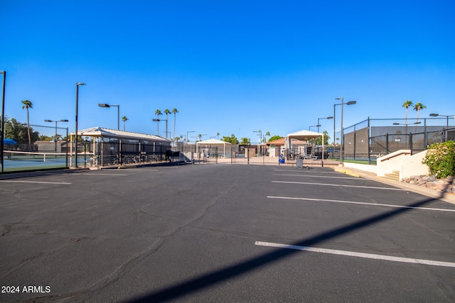 view of vehicle parking featuring tennis court