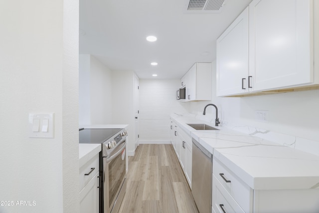 948 S Alma School Rd Unit 1, Mesa, AZ 85210 - kitchen with appliances with stainless steel finishes, light wood-style flooring, white cabinetry, recessed lighting, and light stone countertops