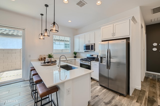23032 E Roundup Way, Queen Creek, AZ 85142 - kitchen with appliances with stainless steel finishes, a kitchen bar, a peninsula, light wood-style flooring, and white cabinetry
