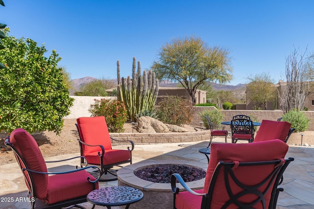 view of patio with outdoor dining space, a fenced backyard, a mountain view, and a fire pit