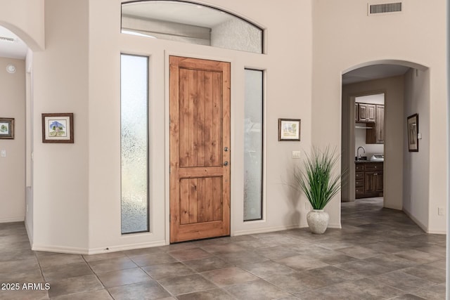 foyer entrance featuring arched walkways, visible vents, and baseboards