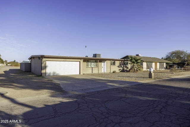 view of front of property featuring cooling unit, an attached garage, and driveway