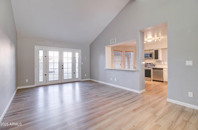 unfurnished living room with light hardwood / wood-style flooring, high vaulted ceiling, and french doors