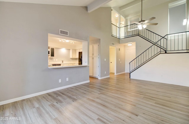 unfurnished living room featuring beam ceiling, ceiling fan, light hardwood / wood-style flooring, and high vaulted ceiling