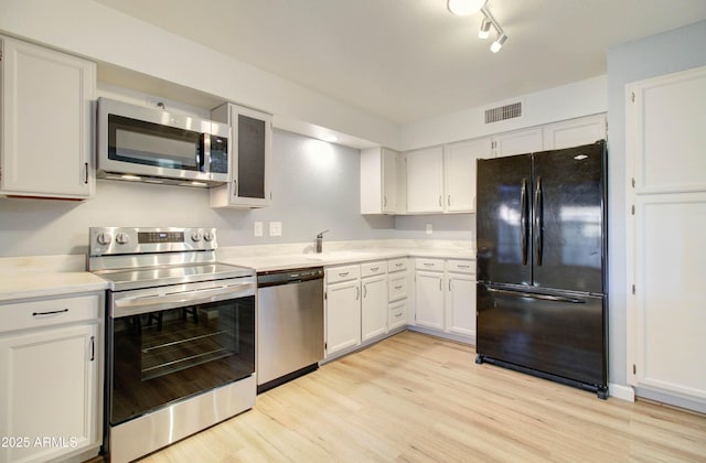 kitchen featuring white cabinets, light hardwood / wood-style floors, appliances with stainless steel finishes, and track lighting