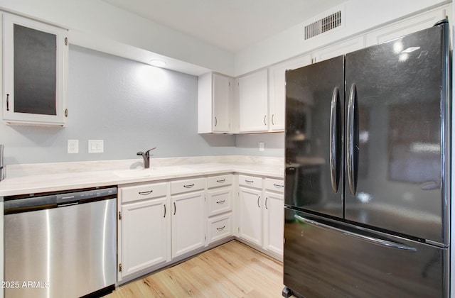 kitchen with black refrigerator, sink, light hardwood / wood-style flooring, dishwasher, and white cabinets