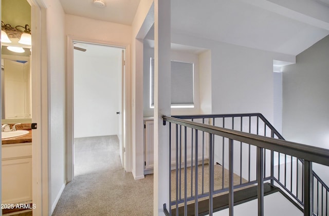 corridor with vaulted ceiling with beams, sink, and light colored carpet