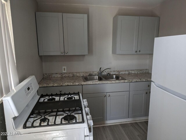 kitchen with dark hardwood / wood-style flooring, sink, white appliances, and gray cabinetry