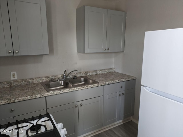 kitchen featuring gray cabinets, dark wood-type flooring, sink, and white appliances