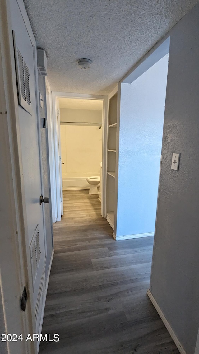 corridor featuring a textured ceiling and dark hardwood / wood-style floors