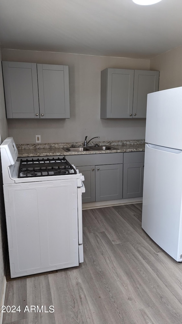 kitchen featuring light hardwood / wood-style floors, sink, white appliances, and gray cabinetry