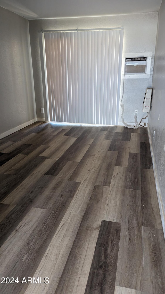 spare room featuring dark wood-type flooring and a wall unit AC