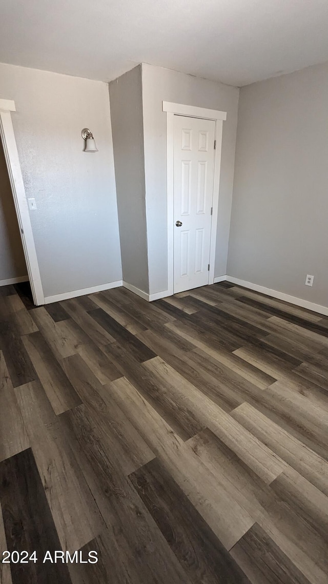 unfurnished bedroom with dark wood-type flooring and a closet