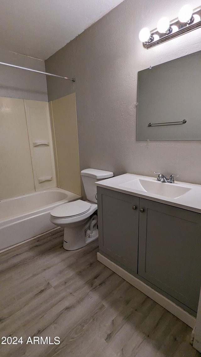 full bathroom with vanity, hardwood / wood-style flooring, washtub / shower combination, and toilet