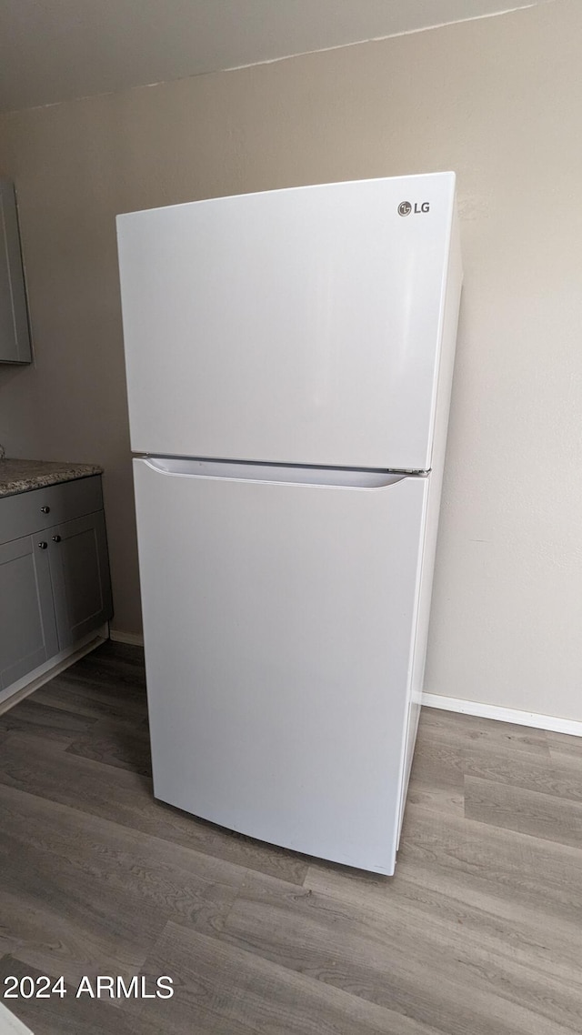 room details with wood-type flooring, gray cabinetry, and white refrigerator