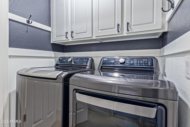 clothes washing area featuring washer and dryer and cabinets