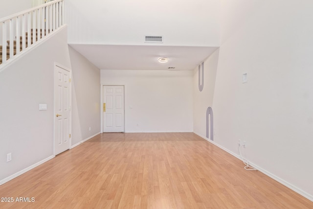 unfurnished room featuring light hardwood / wood-style floors and a high ceiling