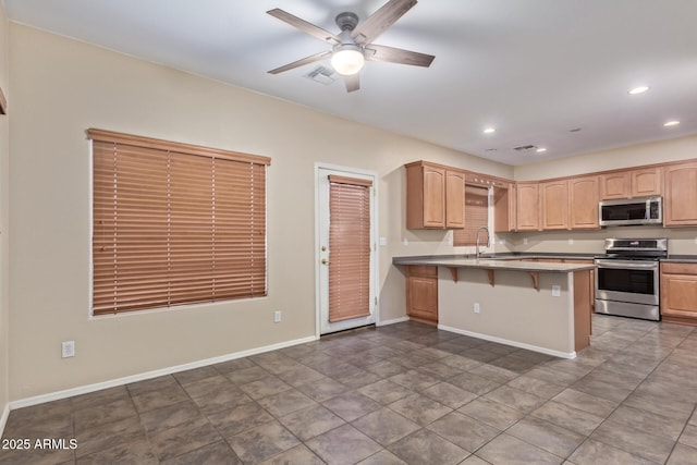 kitchen with a kitchen breakfast bar, sink, kitchen peninsula, stainless steel appliances, and light brown cabinets