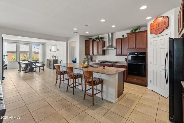 26032 W Quail Ave, Buckeye, AZ 85396 - kitchen with wall chimney range hood, black appliances, recessed lighting, light tile patterned floors, and a kitchen bar