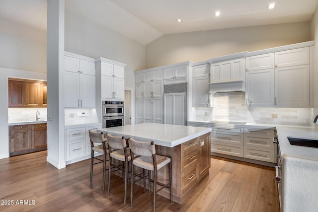 kitchen featuring white cabinetry, sink, a center island, and double oven