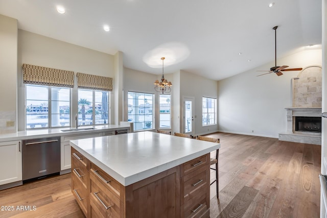 kitchen with sink, white cabinetry, decorative light fixtures, dishwasher, and light hardwood / wood-style floors