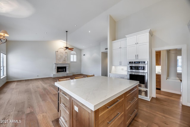 kitchen featuring a kitchen island, double oven, white cabinets, ceiling fan, and light hardwood / wood-style flooring