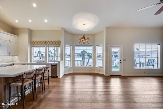 kitchen featuring a breakfast bar, pendant lighting, white cabinetry, sink, and dark hardwood / wood-style flooring