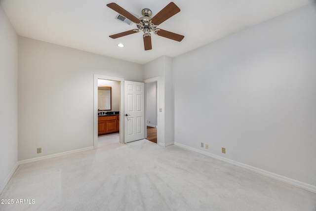 unfurnished bedroom with ceiling fan, light colored carpet, and ensuite bath